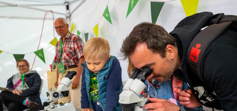 Laps, tema kõrval mees, kes uurib mikroskoobist