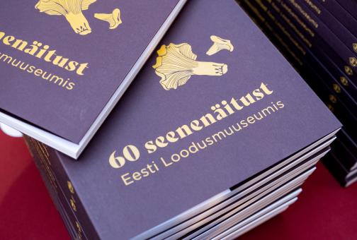 Fotol raamat "60 seenenäitust Eesti Loodusmuuseumis" virnas. Foto Aron Urb